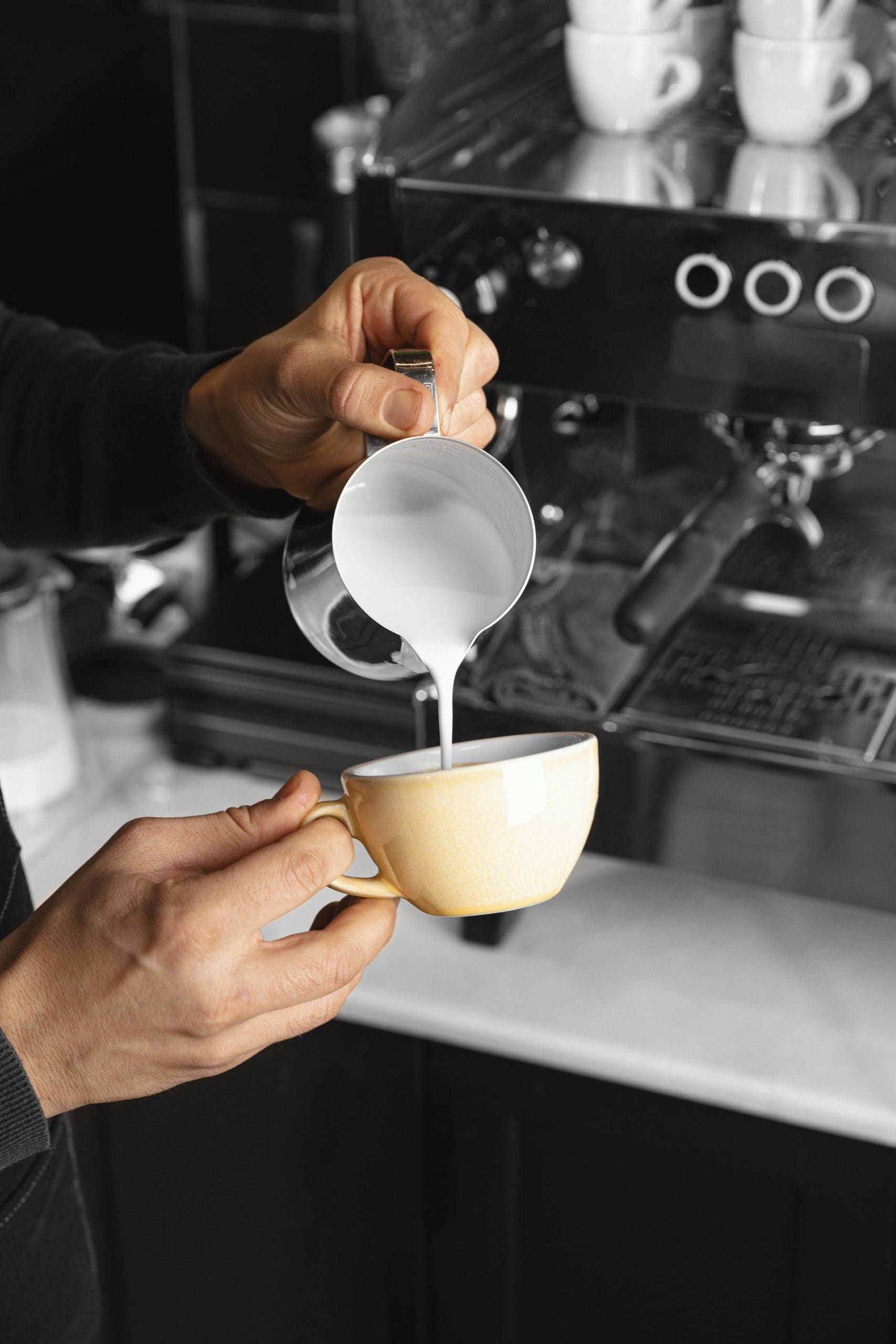 close up hand pouring milk cup scaled